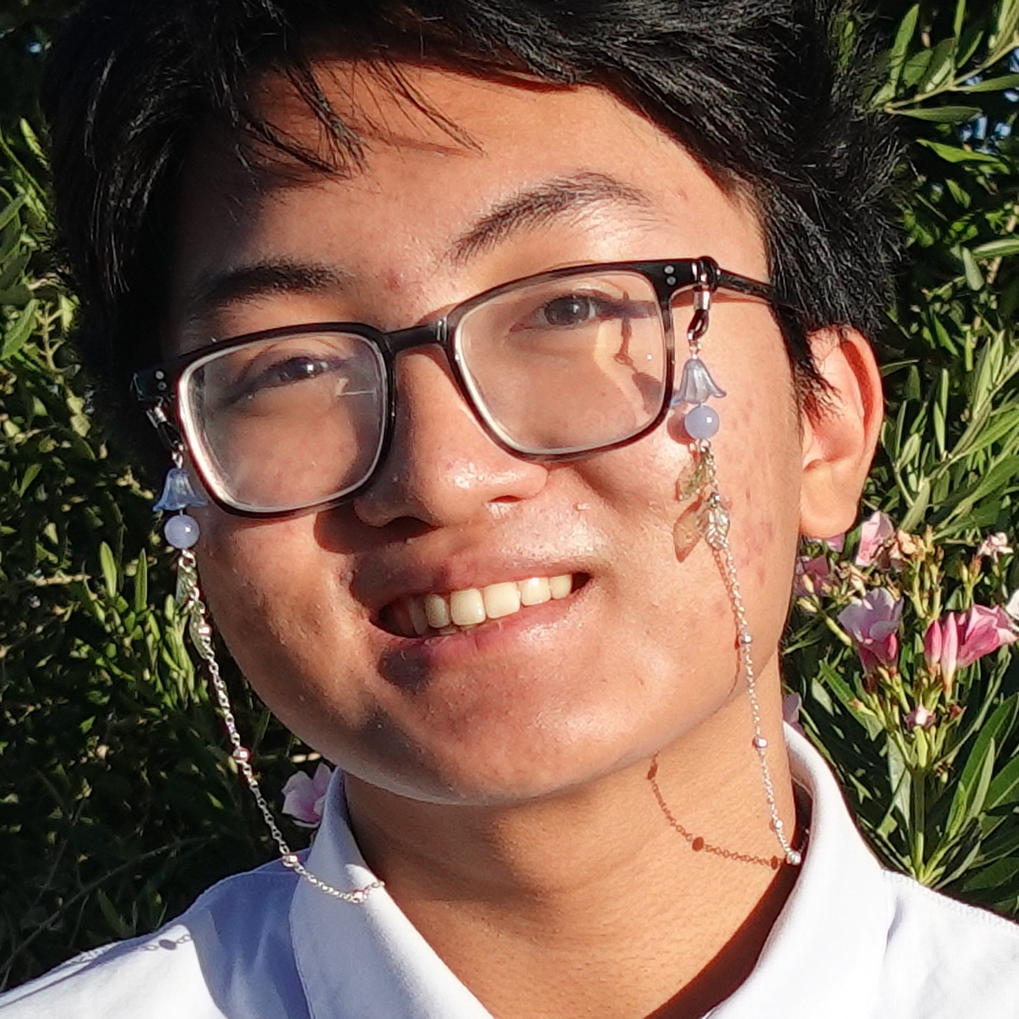 Allan Ilano smiling with pink flora in the background.